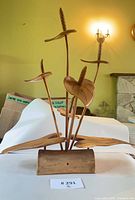Full view of wooden botanical sculpture showing stems, leaves, blooms and base