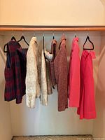 Seven hanging vintage clothing pieces showing colors and styles