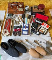 Overview of all items laid out including bow ties, necktie, grooming tools, shoe trees, slippers, boxes