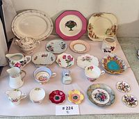 All 25 porcelain pieces laid out showing variety of plates, cups, bowls, creamers and dishes