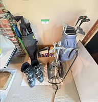 Golf bag with clubs, cart, ski boots and box of accessories