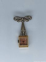 Front view showing bow brooch with rhinestones and watch