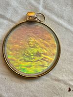 Front view showing holographic deity within round gold-plated frame