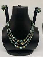Necklace and earrings displayed together on bust