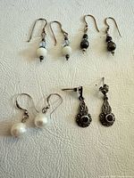 All four pairs of sterling silver earrings laid out on white surface