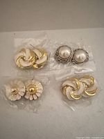 Overview of four earring pairs in plastic sleeves