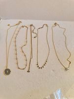 All five gold-tone necklaces laid out to show overall styles and pendants