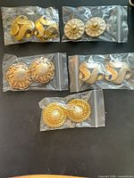 All five pairs of earrings in individual plastic bags on tabletop