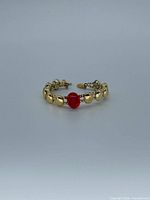 Full bracelet front view displaying gold beads and red centerpiece