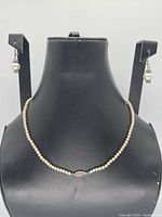 Necklace on display bust with earrings alongside