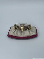 Front view of bracelet on satin cushion showing expansion links and triangular center panel