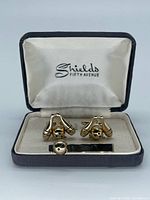 Open case displaying cufflinks, tie bar, and Shields Fifth Avenue logo