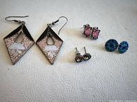 Full view of four pairs of earrings on white surface