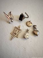 group shot of six sterling silver pendants and charms