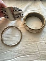 Three bracelets laid out: cuff, wide bangle, thin bangle