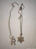 Both sterling silver necklaces laid out showing pendants and chains