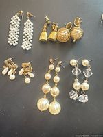 Overview of six pairs of gold-tone vintage dangling earrings on black surface