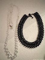 Clear and black bead necklaces laid side by side