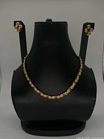 Necklace on display bust with earrings shown for scale