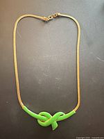 Full view of necklace showing chain and green enamel knot pendant