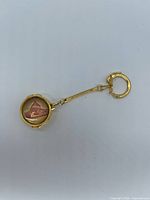 Full view of gold-tone pocket watch style keychain showing clasp, chain, and intaglio front