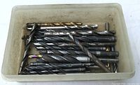 Tray containing assorted sizes of twist drill bits showing coatings and wear