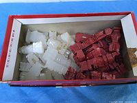 White and red carved stone chess pieces inside cardboard box