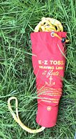Red E-Z Toss bag containing yellow polypropylene rope lying on grass