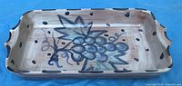 top view of rectangular ceramic dish showing grape design and handle cutouts