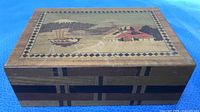 Closed box angled view showing lid artwork and side inlay