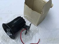 Siren, wiring leads, mounting bracket, and original box visible
