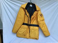Front view of yellow Mustang Marine Wear flotation jacket hanging