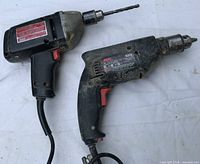 Front view of both corded drills showing brands, models, installed bits and attached cords