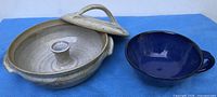 Overall view of covered casserole with lid removed alongside cobalt blue handled bowl