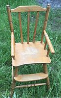 Front view of solid wood high chair showing seat, armrests, spindle back, footrest