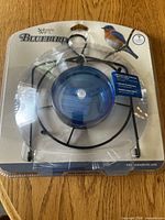Front view of packaged Nature's Way Bluebird feeder showing blue dish and metal frame