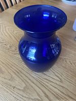 Side view of cobalt blue glass vase on wooden table