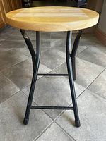 full view of stool front showing wood seat and black steel legs
