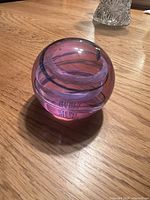 Front angled view of spherical Caithness paperweight showing pink-white swirl inside clear glass