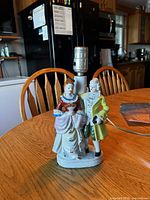 Front view of porcelain courting couple lamp on wooden table