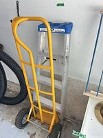 Hand truck leaning against ladder showing both items together