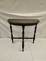 Front angled view showing full three-leg table with scalloped top