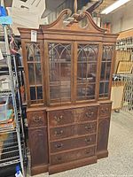 Full view of mahogany secretary desk showing upper glazed cabinet, lower drawers, and pediment