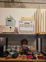 Top shelf showing plastic basket, two cardboard boxes, envelopes and vertical wooden dowels