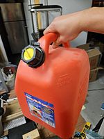 Front view showing capacity label, handle, black cap, yellow pour spout
