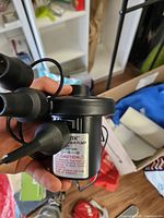 Close-up of AGPTEK pump body with caution label and attached nozzles