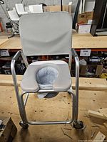 Front view showing aluminum frame, U-seat, backrest, bucket and casters