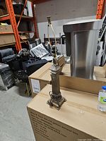 full view of brass lamp on cardboard box showing entire form and cord