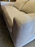 Front angle showing beige woven fabric, seat cushion, armrest