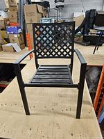 Front view of black aluminum lattice-back patio armchair on worktable